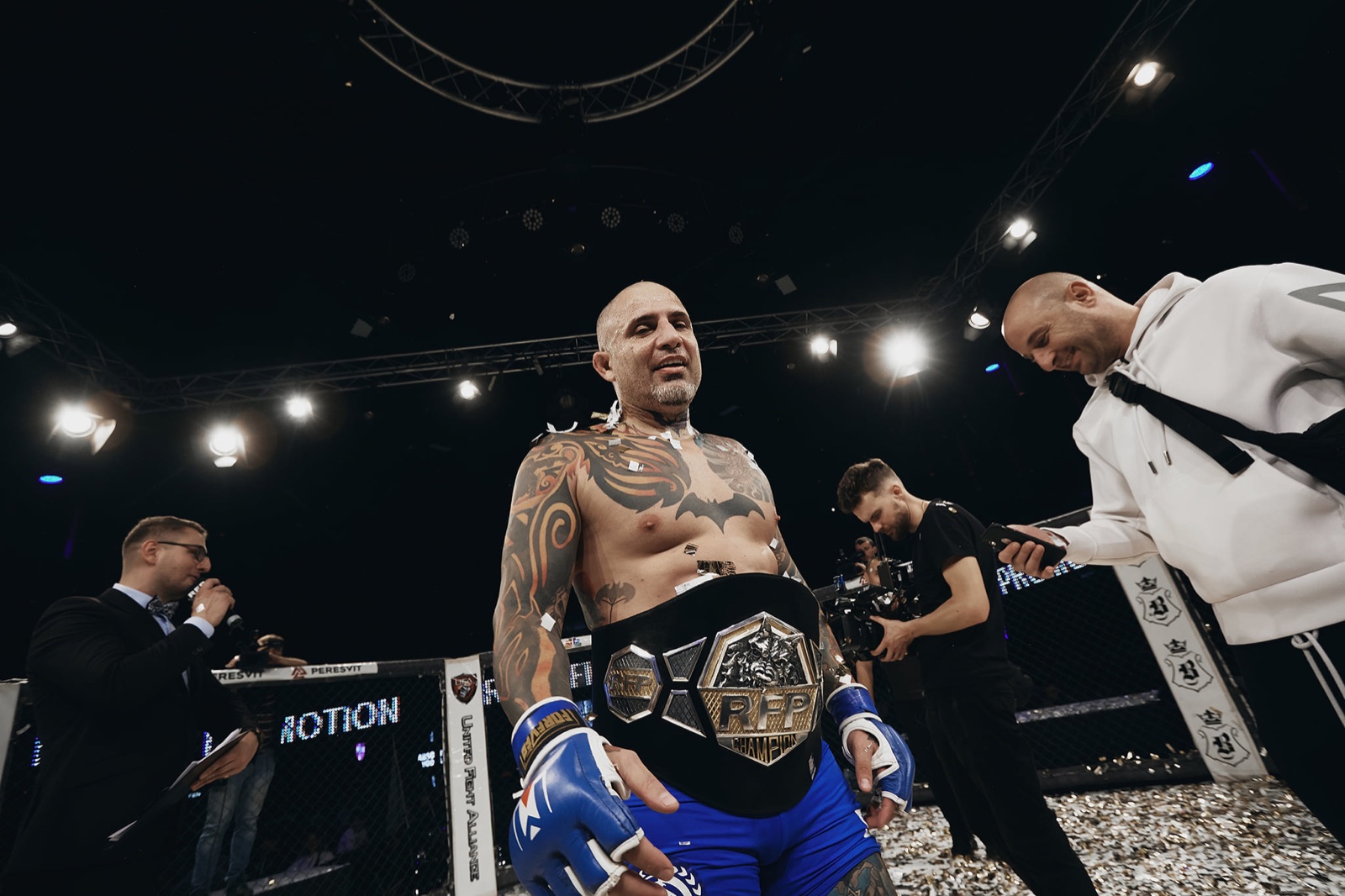 A decorated fighter presents a championship belt after the bout.