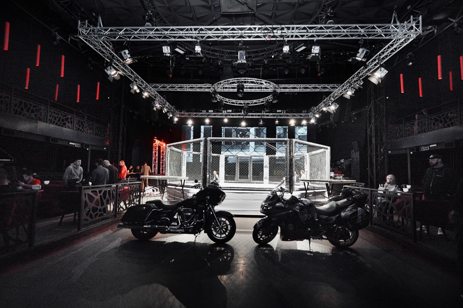 An illuminated cage and motorcycles in an empty arena before the event.