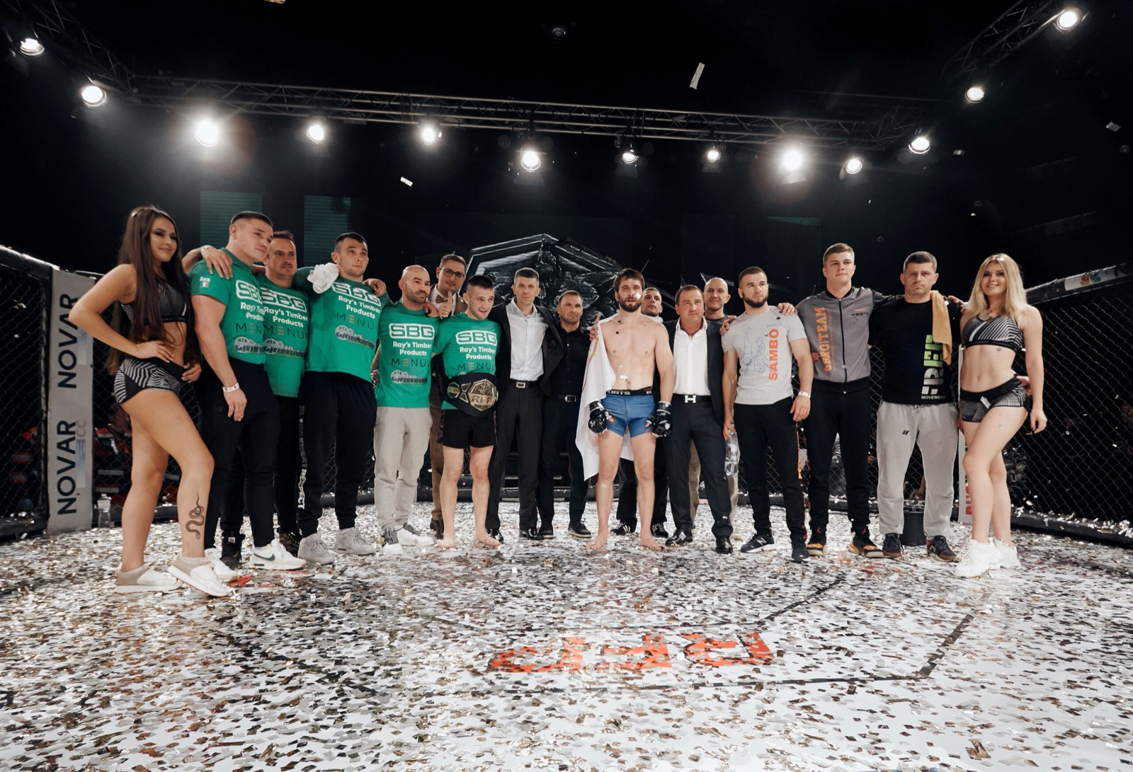 A large group of fighters, coaches and organizers inside the cage after an event.