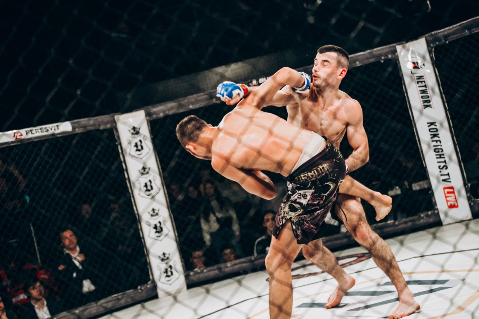 Two MMA fighters in a dynamic exchange as one attacks with a knee.